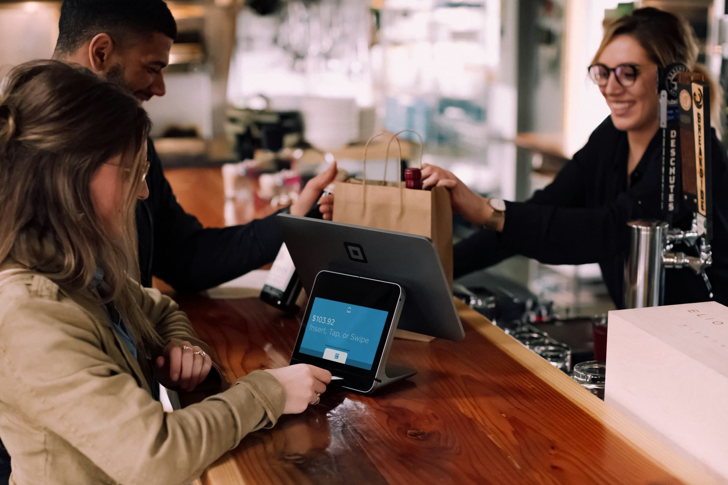 A supporter confirming a payment on a counter screen while staff hand over an order