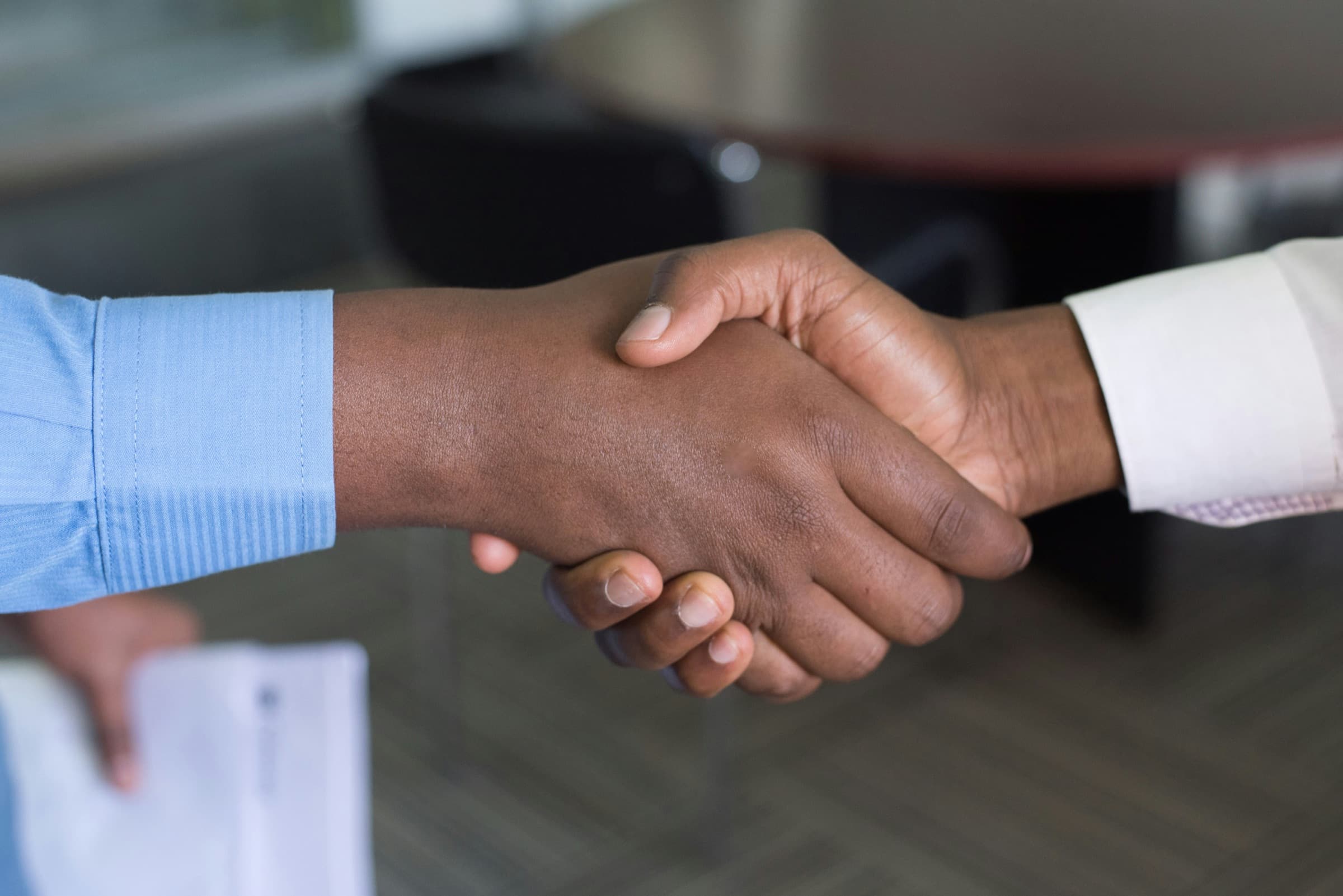 Two people shaking hands across a table