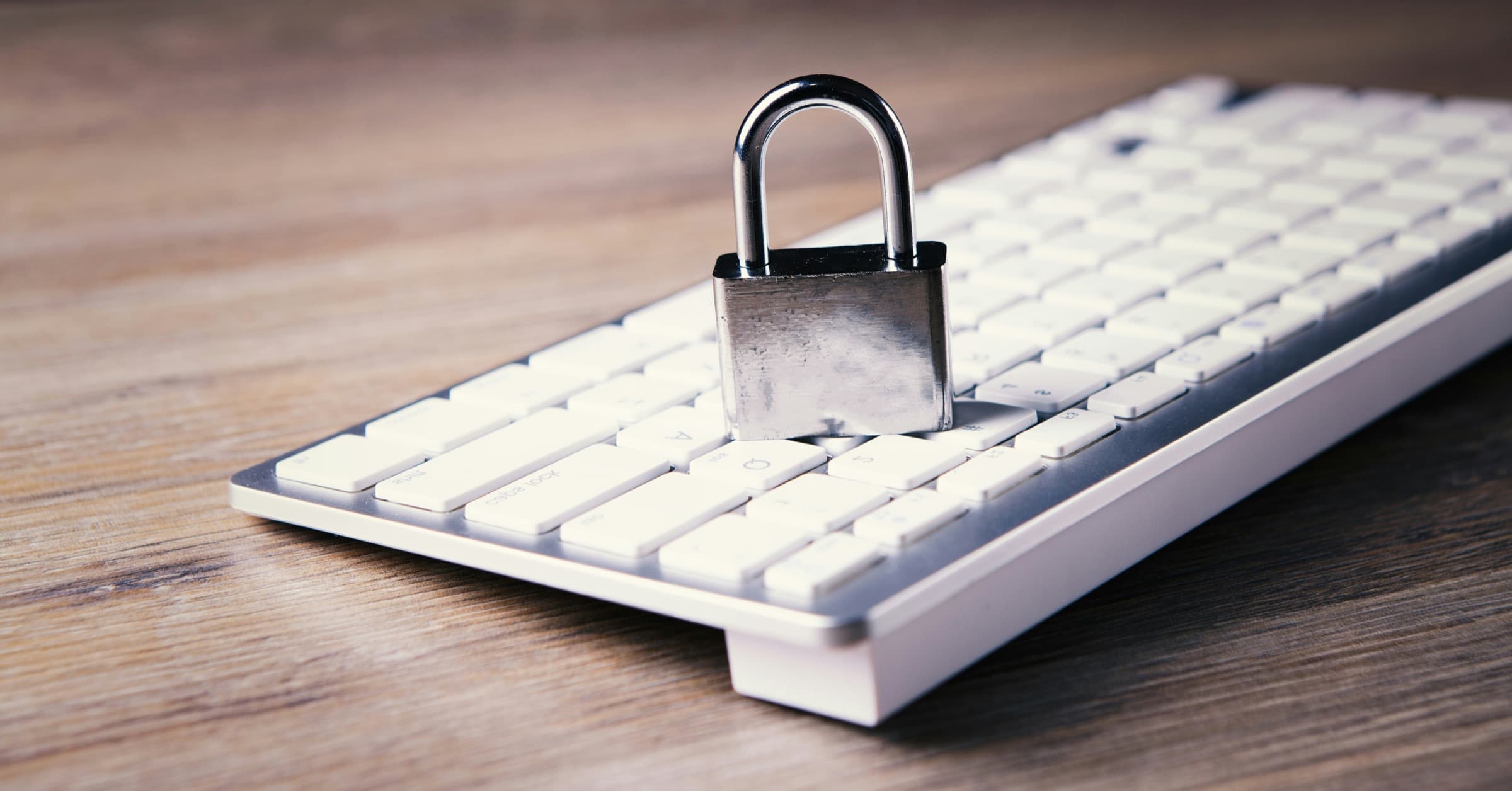 A small padlock standing on a white keyboard