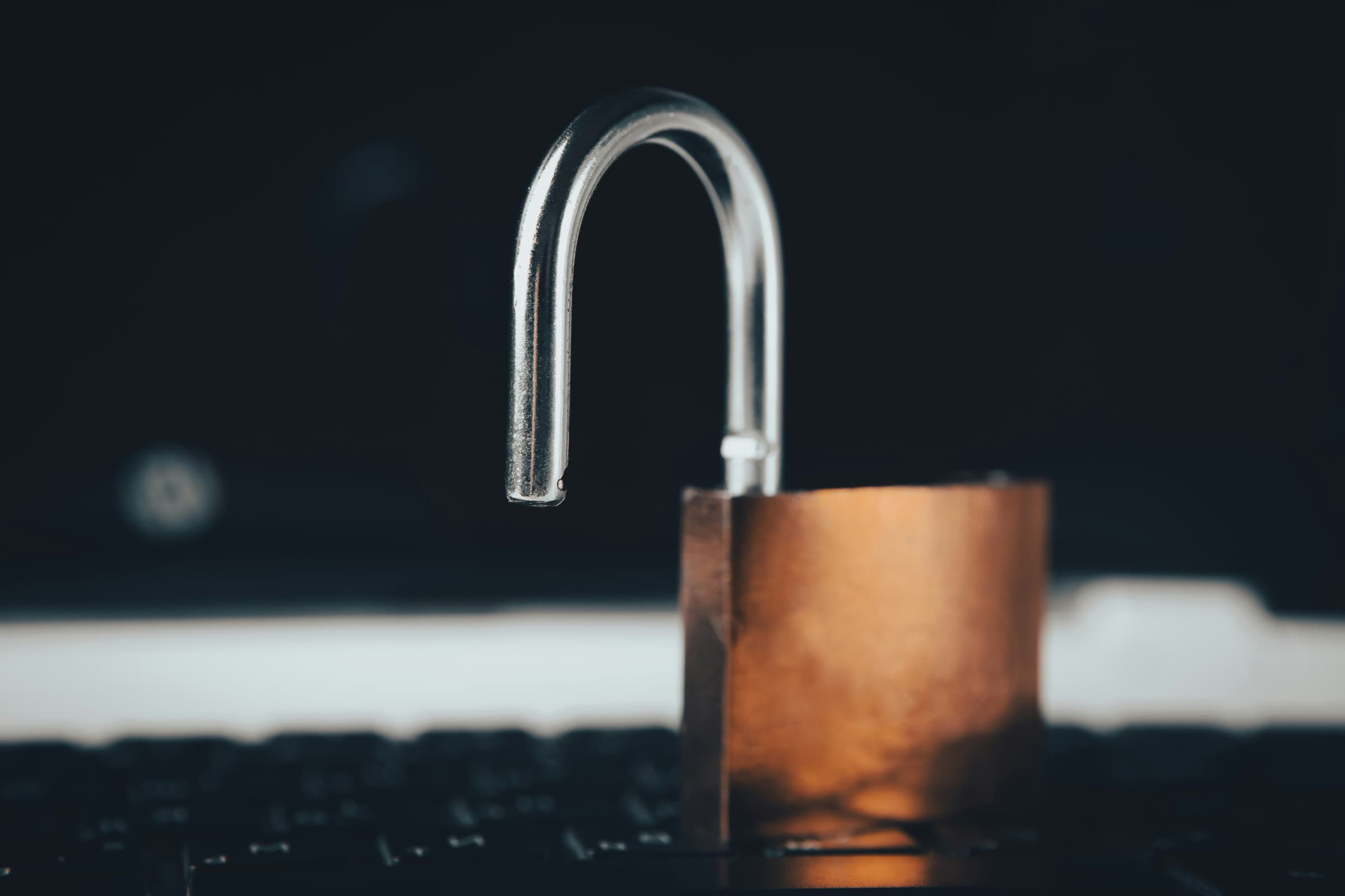 An open padlock resting on a keyboard in low light